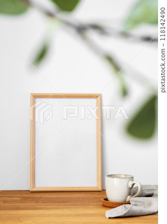 A frame with a blank canvas against a light wall and on a wooden tabletop A frame with a blank canvas against a light wall and on a wooden tabletop 118142490