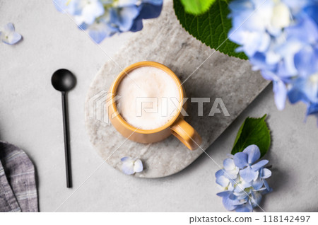 Spring bouquet with blue hydrangea flowers and a cup of cappuccino coffee in a yellow cup and spoon Spring bouquet with blue hydrangea flowers and a cup of cappuccino coffee in a yellow cup and spoon 118142497