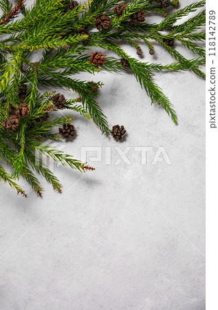 Flat lay fir tree. Decoration of a coniferous branch and pine cones on a gray textural background. Flat lay fir tree. Decoration of a coniferous branch and pine cones on a gray textural background. 118142789