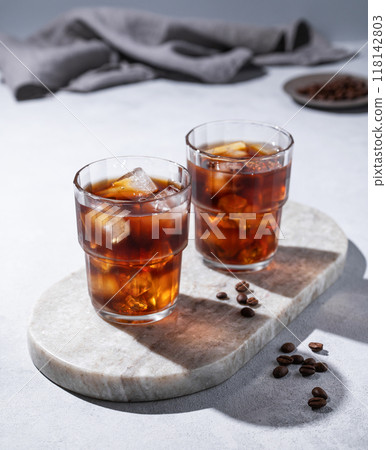 Cold brew coffee in a two glasses with ice on a marble board on a light background with coffee beans 118142803