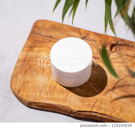 Organic cosmetic cream for body and face skin in a jar on a wooden board with green leaves. Organic cosmetic cream for body and face skin in a jar on a wooden board with green leaves. 118143034