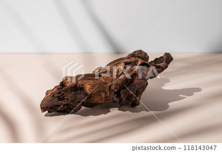 A piece of natural wood with a complex texture on a beige background with shadow. A piece of natural wood with a complex texture on a beige background with shadow. 118143047