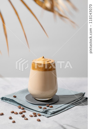 Dalgona coffee. Whipped instant coffee in a glass with beans and palm leaf shadow 118143070