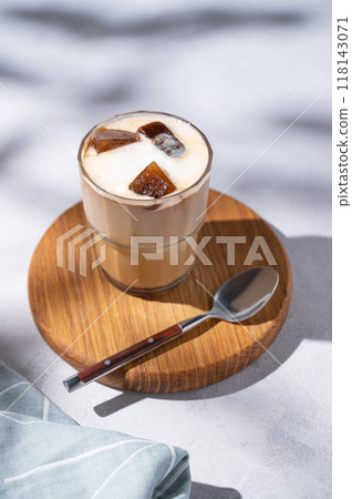 Iced coffee latte in a glass with milk on a wooden board on a light background with Iced coffee latte in a glass with milk on a wooden board on a light background with 118143071