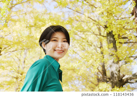 一位年輕女子正在欣賞銀杏樹的秋葉 118143436