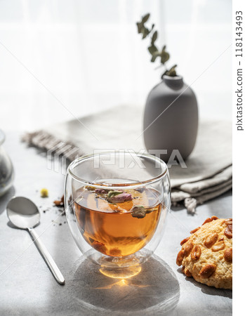 A glass of herbal tea and homemade cookies on the background of a window with morning sunlight. 118143493