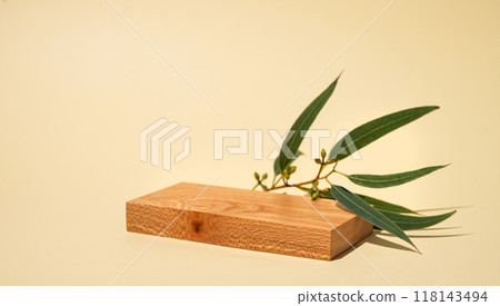 Empty wooden board with shadows and green leaves on a yellow background with shadow. Empty wooden board with shadows and green leaves on a yellow background with shadow. 118143494