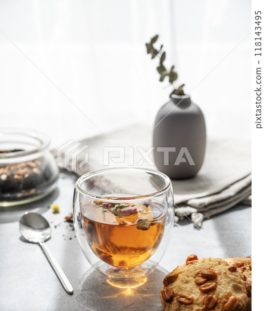 A glass of herbal tea and homemade cookies on the background of a window with morning sunlight. 118143495