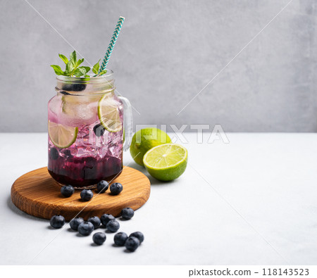 Blueberry mojito or lemonade with lime, ice and mint in a glass on wooden board on light background 118143523