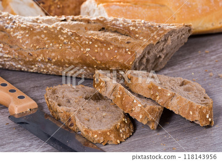 Slices of wheaten bread and knife on wooden surface 118143956