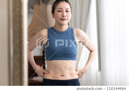 穿著運動服的女人在鏡子前關心自己的身材 穿著運動服的女人在鏡子前關心自己的身材 118144664