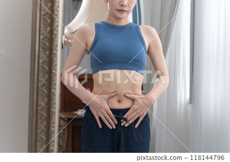 穿著運動服的女人在鏡子前關心自己的身材 118144796