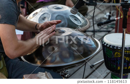 A musician skillfully plays the handpan at an outdoor event A musician skillfully plays the handpan at an outdoor event 118145613
