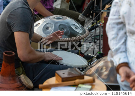 Musicians perform with handpan and tambourine at an outdoor gathering 118145614
