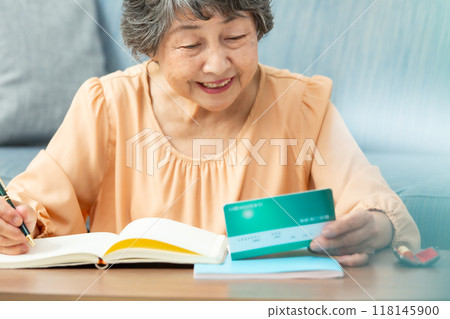 Worried senior woman, bankbook, end of life planning 118145900