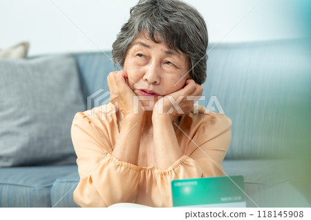 Worried senior woman, bankbook, end of life planning 118145908