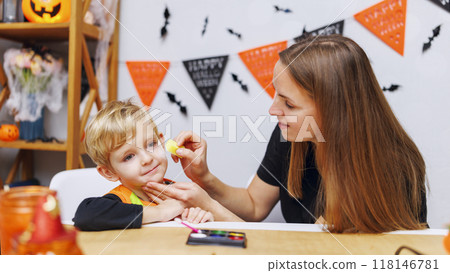 Mother painting child's face for Halloween party Mother painting child's face for Halloween party 118146781