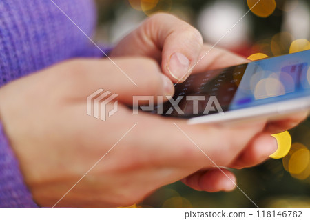Woman typing on smartphone with Christmas lights Woman typing on smartphone with Christmas lights 118146782