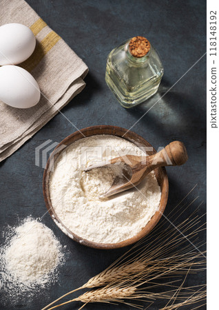Wheat flour in a wooden bowl with a scoop on a dark blue background with eggs  118148192