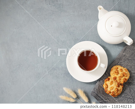 A cup of fragrant tea with homemade cookies and a white teapot on a blue background. A cup of fragrant tea with homemade cookies and a white teapot on a blue background. 118148213