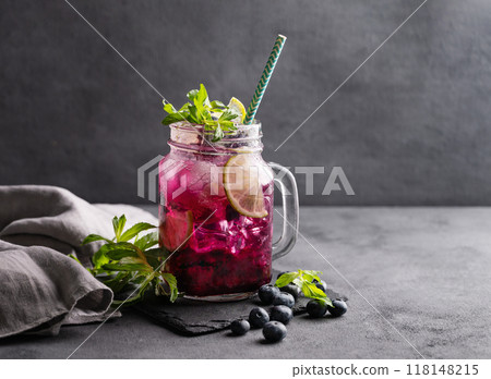 Refreshing blueberry mojito or lemonade with lime, mint and ice on a dark background.  118148215