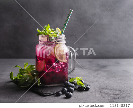 Refreshing blueberry mojito or lemonade with lime, mint and ice on a dark background.  118148217