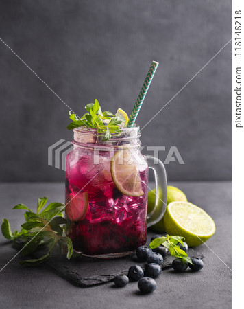 Refreshing blueberry mojito or lemonade with lime, mint and ice on a dark background.  118148218