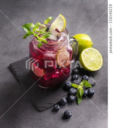 Refreshing blueberry mojito or lemonade with lime, mint and ice on a dark background.  118148219
