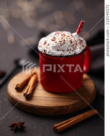Red mug with hot chocolate or cocoa with whipped cream on a wooden stand with cinnamon sticks Red mug with hot chocolate or cocoa with whipped cream on a wooden stand with cinnamon sticks 118148372