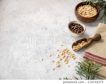 Flat lay of pine nuts in a bowl and wooden scoop  on a napkin on a light texture background 118148375