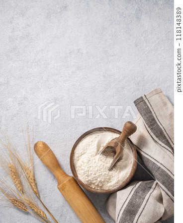 Natural flour in a wooden bowl with a scoop, rolling pin and napkin on a blue background Natural flour in a wooden bowl with a scoop, rolling pin and napkin on a blue background 118148389