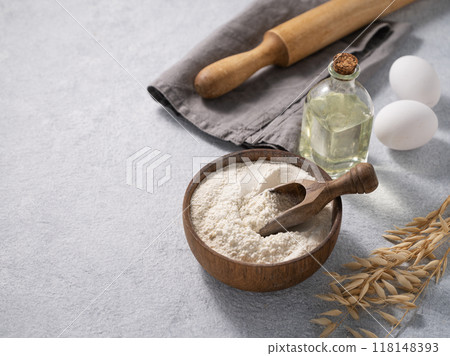 Oatmeal in a wooden bowl with a scoop, eggs and rolling pin on a blue background Oatmeal in a wooden bowl with a scoop, eggs and rolling pin on a blue background 118148393