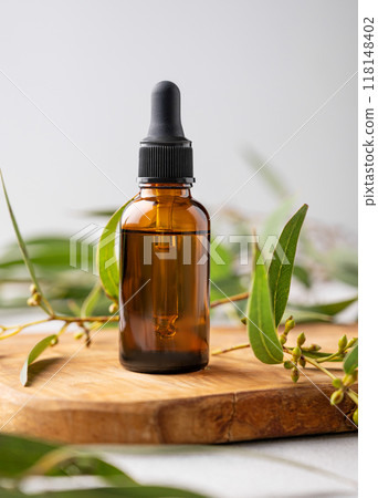 Face and body serum in bottle on a wooden board with green leaves. Face and body serum in bottle on a wooden board with green leaves. 118148402