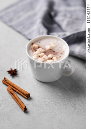 White mug of hot cocoa or chocolate with whipped cream and marshmallows, cinnamon sticks  118148554
