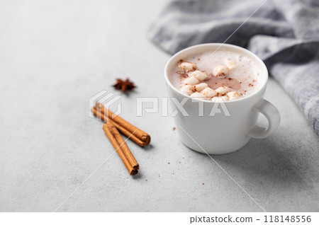 White mug of hot cocoa or chocolate with whipped cream and marshmallows, cinnamon sticks 118148556
