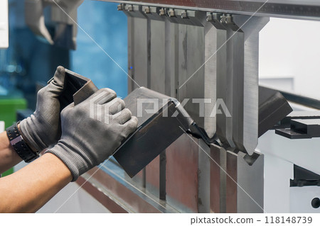 Close up the press brake bending machine operator hold the sheet metal parts with safety glove. 118148739