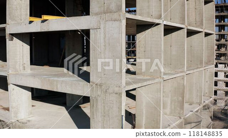 Concrete construction of a new high-rise apartment building. An unfinished buildings facade view from outside. Residential complex exterior. Real estate investment. Slabs, walls without windows Concrete construction of a new high-rise apartment building. An unfinished buildings facade view from outside. Residential complex exterior. Real estate investment. Slabs, walls without windows 118148835