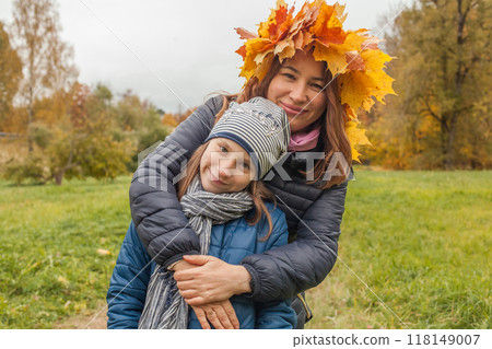 A portrait of smiling mother with a small daughter in autumn nature outdoors A portrait of smiling mother with a small daughter in autumn nature outdoors 118149007