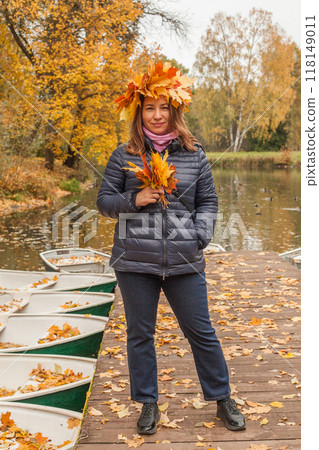 Walking woman in yellow leaves wreath outdoors on autumn background, portrait Walking woman in yellow leaves wreath outdoors on autumn background, portrait 118149011