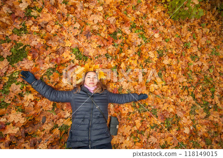 Joyful autumn woman in fall yellow leaves wreath relaxing in autumn background 118149015