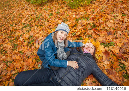 Cheerful mother with daughter in autumn day on yellow fall leaves background Cheerful mother with daughter in autumn day on yellow fall leaves background 118149016