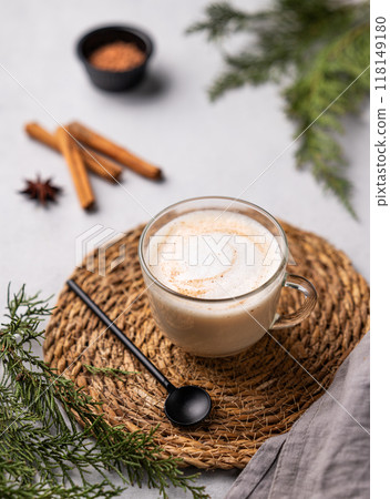 Spiced coffee latte or cappuccino with cinnamon sticks on a light background with fir branches. 118149180
