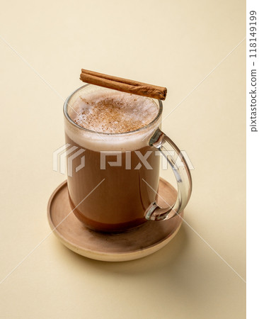 Glass cup of hot chocolate with whipped cream and cinnamon stick  on a yellow background. 118149199
