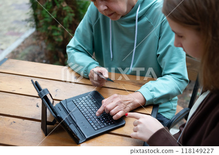 The granddaughter teaches the grandmother to use the tablet . 118149227