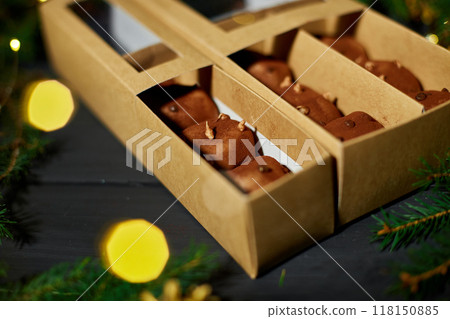 Homemade Chocolate Treats Packaged in a Festive Box Surrounded by Pine Branches and Holiday Decorations 118150885