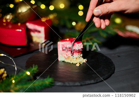 A Person Cutting a Slice of Vibrant Layered Cake on a Black Plate Adorned With Festive Decorations A Person Cutting a Slice of Vibrant Layered Cake on a Black Plate Adorned With Festive Decorations 118150902