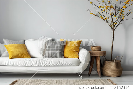 White sofa with grey plaid and yellow pillows against grey wall 118152395