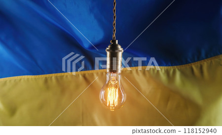 Edison light bulb on Ukrainian flag background. Bad electricity supply, problems, energy crisis in Ukraine, blackout because of war, shelling Edison light bulb on Ukrainian flag background. Bad electricity supply, problems, energy crisis in Ukraine, blackout because of war, shelling 118152940