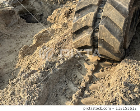 A close-up of large excavator tracks in the dirt on a construction site A close-up of large excavator tracks in the dirt on a construction site 118153612