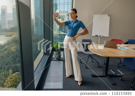 A Stylish Woman Taking a Selfie in a Modern and Contemporary Office Setting Environment A Stylish Woman Taking a Selfie in a Modern and Contemporary Office Setting Environment 118153895